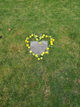 Artificial flowers in the shape of a heart lie next to the tombstone in the cemetery..