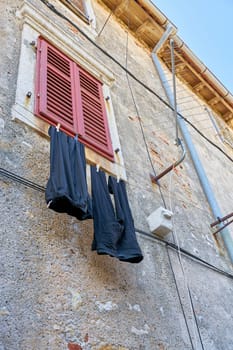 Clothesline with pants on a facade in the old town of Krk in Croatia