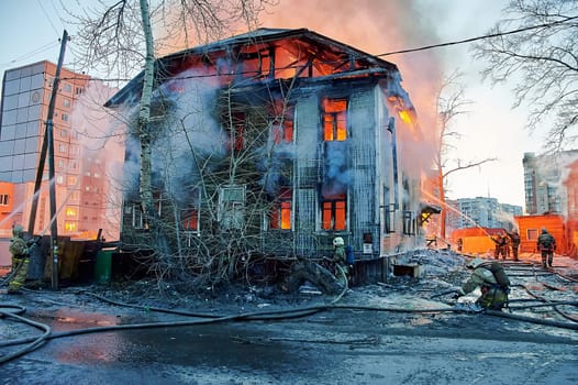 Firefighters extinguish a fire in a two-story wooden house. High quality photo