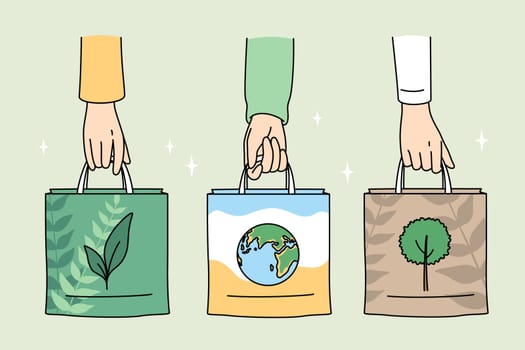 Ecology care and eco-friendly things concept. Human hands holding eco-friendly bags with pictures of plant planet and tree vector illustration