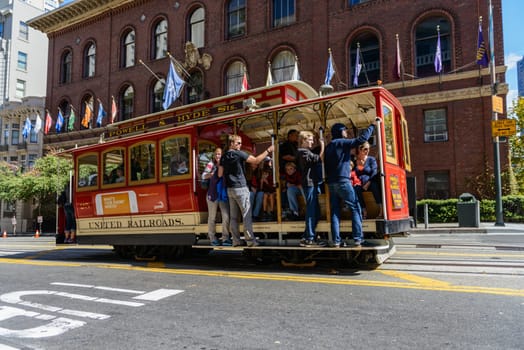 SAN FRANCISCO - OCT 06: Passengers enjoy a ride in a cable car on Oct 06, 2012 in front of famous Transamerica building in San Francisco. It is the oldest mechanical public transport in San Francisco which is in service since 1873.