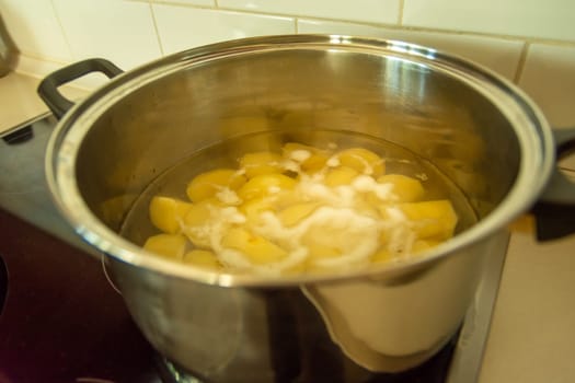 Cooking a peeled potato in water in a silver big pot