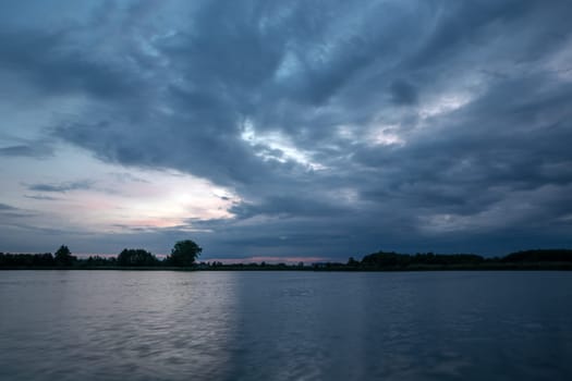 Dark evening clouds landscape over the lake, spring view