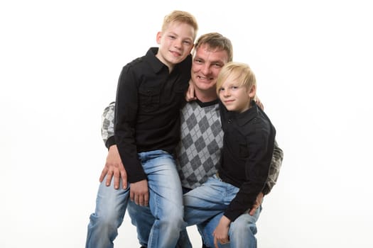 Half-length portrait of a father and two sons in casual clothes on a white background
