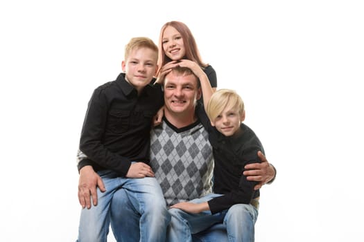 Half-length portrait of a father and three children in casual clothes on a white background