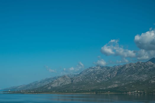 Beautiful coast, blue sea and mountains in the distance. Nice view of the blue Adriatic sea during a sunny day.