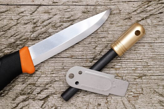 fire starter and camping knife on grungy wooden background
