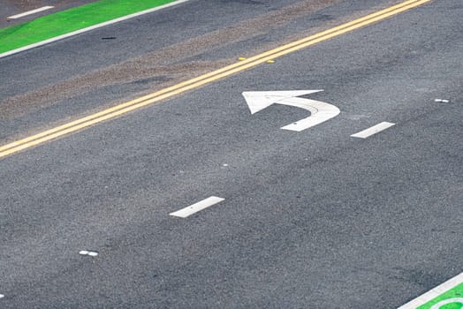 Asphalt of road close up detailed view. Yellow and white line on black with turn sign arrow