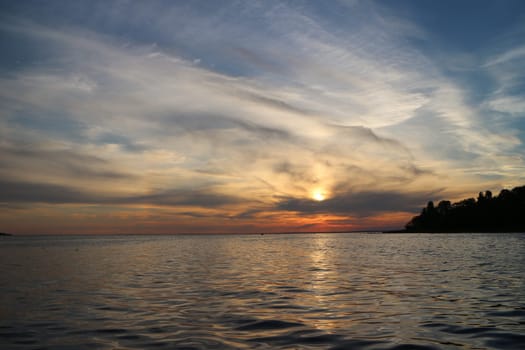 picturesque sunset, bizarre clouds illuminated by the setting sun, sea view