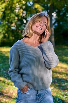 Beautiful woman talking on the phone in the park in summer. High quality photo