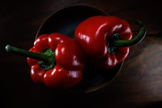 Two red pepper in bowl with dark backround