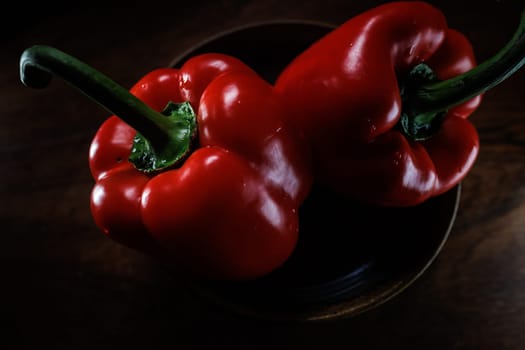 Two red pepper in bowl with dark backround