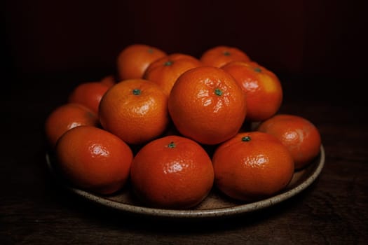 Many mandarin oranges on plate and wooden table