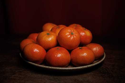 Many mandarin oranges on plate and wooden table