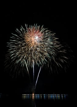 Colorful fireworks exploding with reflection on lake