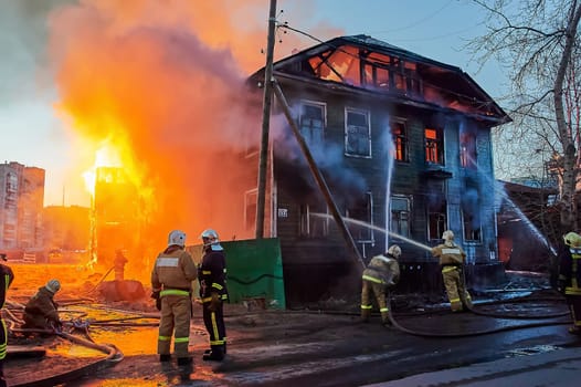 Firefighters extinguish a fire in a two-story wooden house. High quality photo