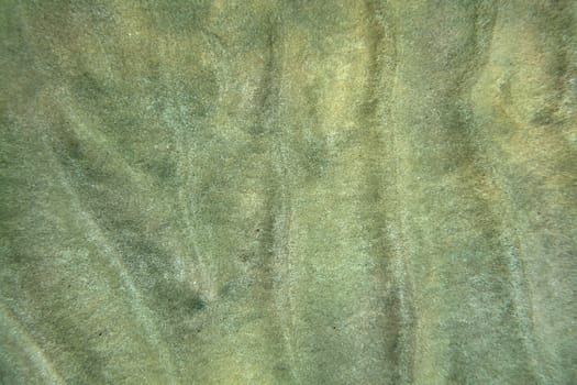 Sea bottom - sand "dunes"" and ripples in shallow ocean water, underwater view from above. Abstract marine background."