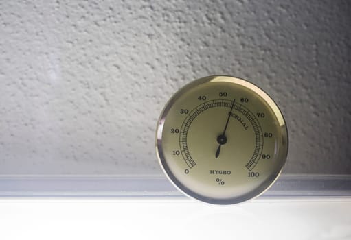 Analog hygrometer attached to glass museum cabinet. Selective focus