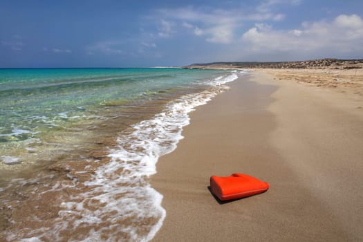 Bright red plastic oil (or washing liquid) container on beautiful unspoiled beach. Sea plastics littering concept. Karpazz, Northern Cyprus.