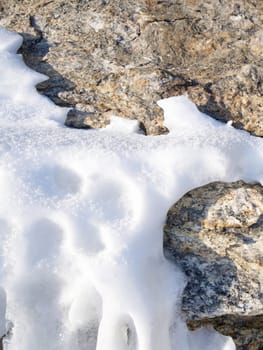 The surface of the rocky mountain is covered with ice and snow. Lake Baikal, Russia