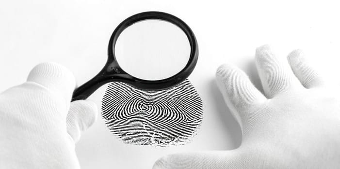 The Criminology expert through a magnifying glass looking at a fingerprint