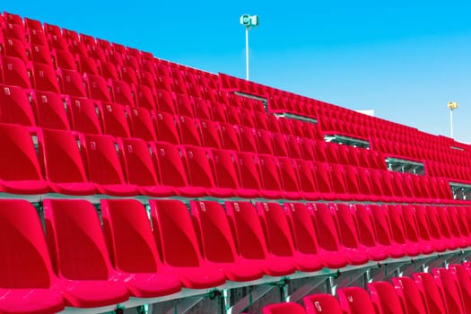 The Rows of empty red color plastic stadium seating on the terrace.