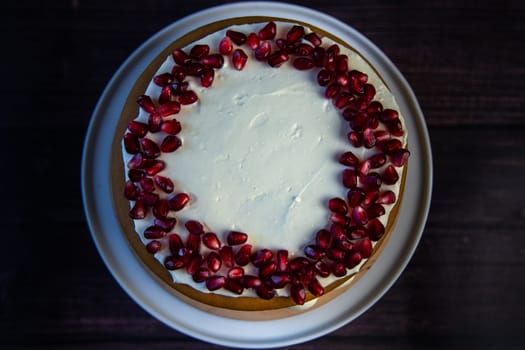 Cake of three layers, consisting of cakes and white cream, decorated with pomegranate on top, top view. High quality photo