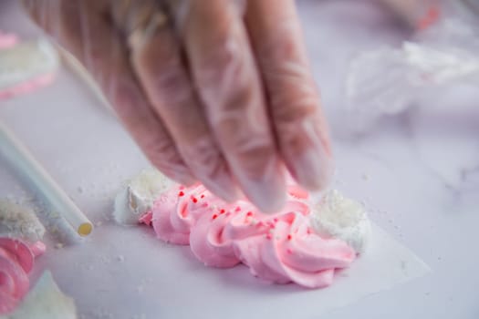 Pink meringue hats with white pompoms and brims are sprinkled with white balls on the side, against a parchment background. High quality FullHD footage