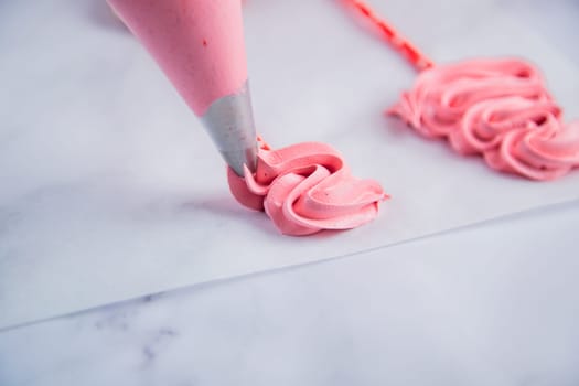 From the pastry bag, a pink bizet is laid out on baking paper with curls in the form of a Christmas tree. High quality photo