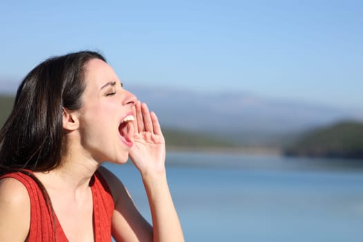 Side view portrait of a woman screaming loud in a lake