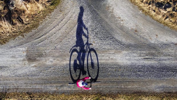 Aerial shot with drone of female cyclist on road with shadow