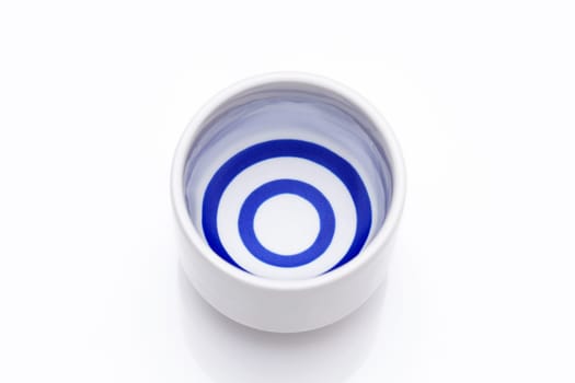 Japanese sake in a traditional ceramic ochoko cup on white background
