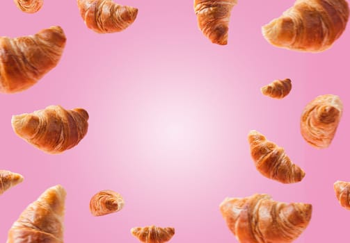 Many freshly baked croissants levitating or flying. Croissants isolated on pink background. Levitation scene. Copy space place for text. Advertisement of bakery, confectionery. Creative breakfast food