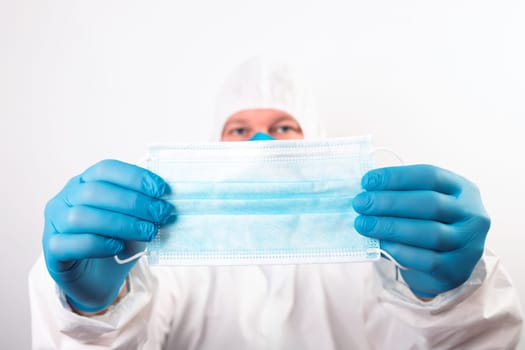 Doctor hand wear blue medical gloves holds antivirus face mask for pandemic diseases. Outbreak, Covid19 concept