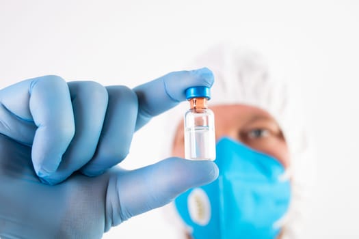 COVID-19 coronavirus vaccine. Vaccination concept. Doctor's hand in blue gloves hold medicine vaccine vial bottle and syringe.