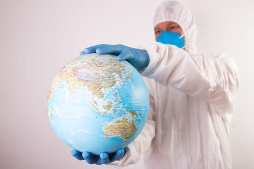 World epidemic danger concept. Male doctor man in medical face mask and gloves protecting planet Earth.