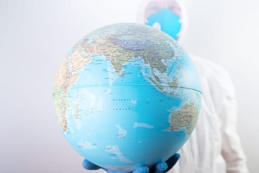 World epidemic danger concept. Male doctor man in medical face mask and gloves protecting planet Earth.