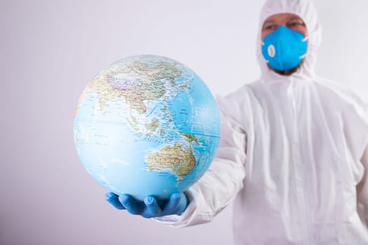 World epidemic danger concept. Male doctor man in medical face mask and gloves protecting planet Earth.