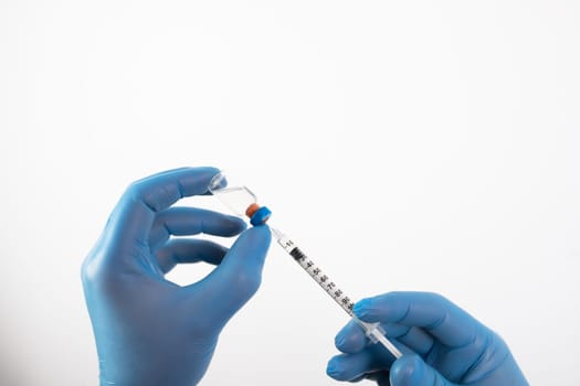 COVID-19 coronavirus vaccine. Vaccination concept. Doctor's hand in blue gloves hold medicine vaccine vial bottle and syringe.