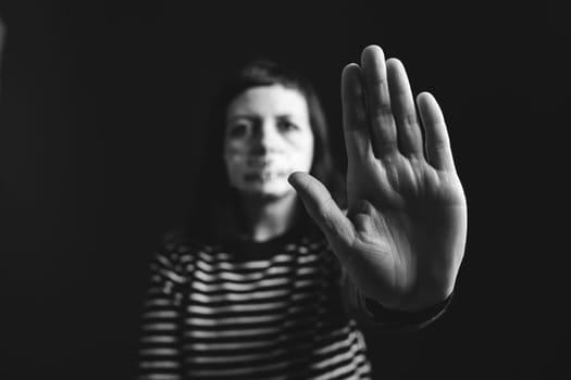 Women violence and abused concept. Stop domestic violence against women and human trafficking.Woman with tape on mouth and stop violence text