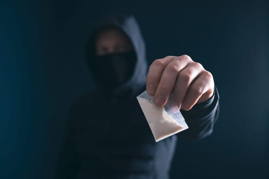 Hand of addict man holding a dose of cocaine or heroine. Concept of drug dealer, drug trafficking, crime, addiction and sale.
