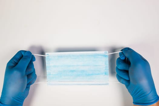 Doctor hand wear blue medical gloves holds antivirus face mask for pandemic diseases. Outbreak, Covid19 concept