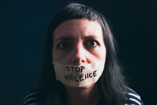 Women violence and abused concept. Stop domestic violence against women and human trafficking.Woman with tape on mouth and stop violence text