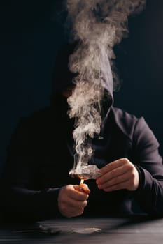 Addict/junkie man preparing drugs. The concept of crime and drug addiction.