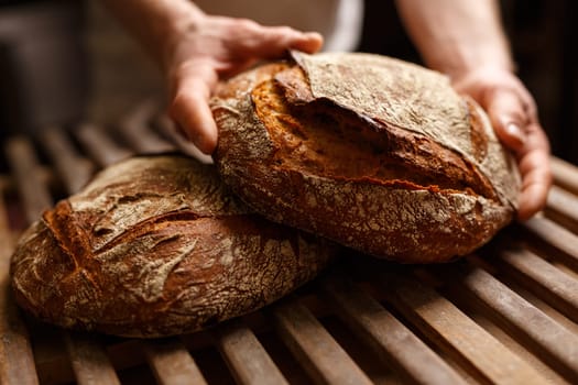 Hands holding organic bread in authentic bakery setting
