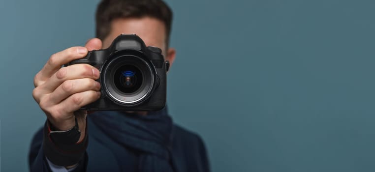 Photographer holding dslr camera on blue modern backround