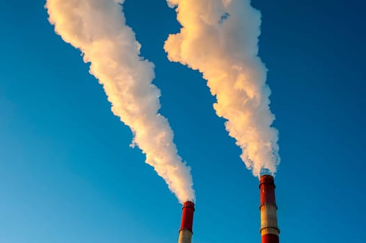 white smoke is coming out of the pipes in the blue sky. High quality photo