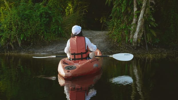 Back young adult woman paddling kayaking canoe on a lake on summer day in rural landscape, adventure travel leisure enjoying concept, lifestyle sport vacation