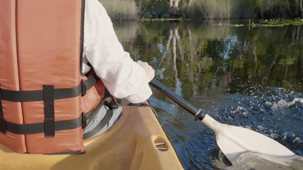 Close up back young adult woman paddling kayaking canoe on a lake on summer day in rural landscape, adventure travel leisure enjoying concept, lifestyle sport vacation