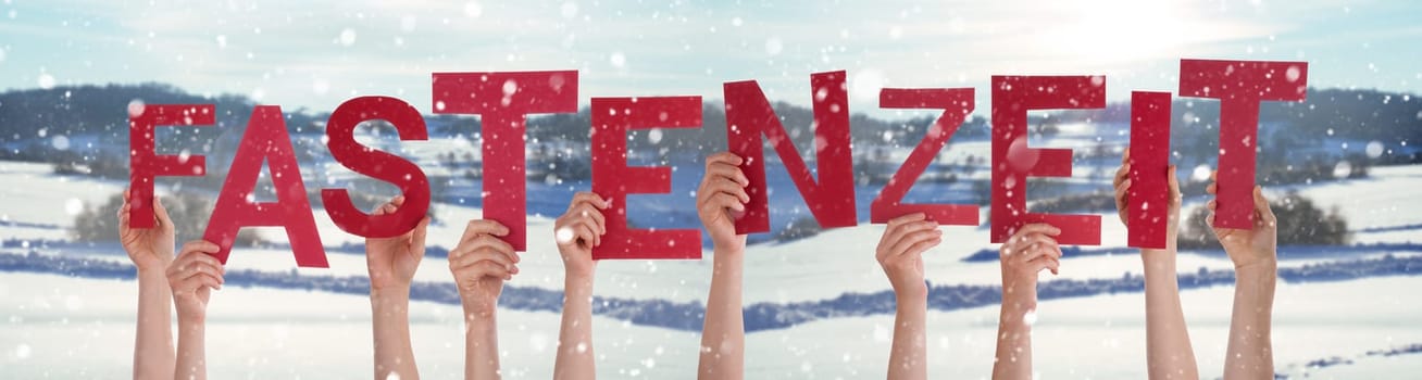 People Hands Holding Red German Word Fastenzeit Means Fasting. Snowy Winter Background With Snowflakes